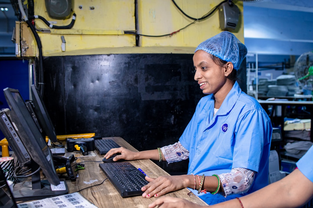 a woman works on a computer in a factory facilities dashboard work orders asset maintenance operations team