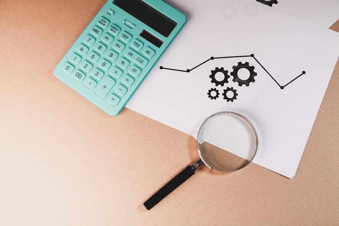 calculator magnifying glass and chart with gears on paper pricing comparison software budget facilities management business planning