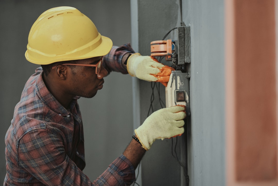 electrician installing wiring with yellow hardhat technician installation wall mounted intercom safety equipment