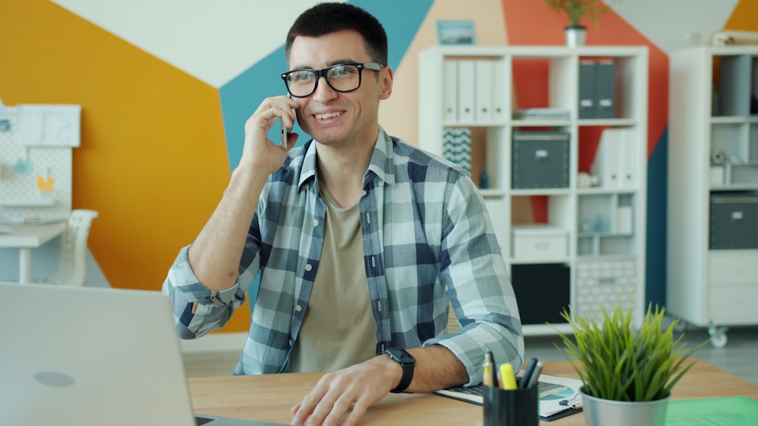 man in glasses talking on phone at desk support agent headset customer conversation service desk