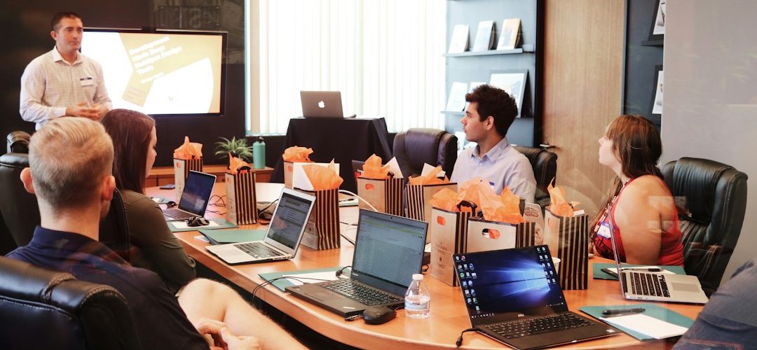 man standing in front of people sitting beside table with laptop computers sales training comparison remote coaching platform selection team growth