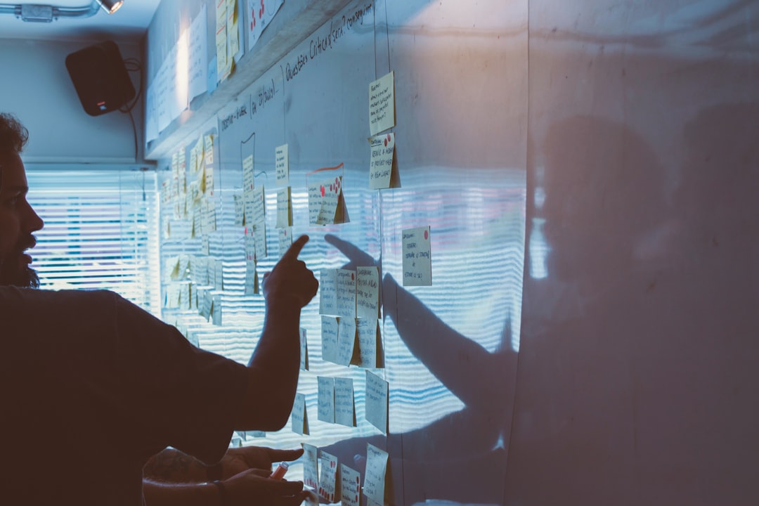 person pointing white paper on wall marketing team planning session strategy board
