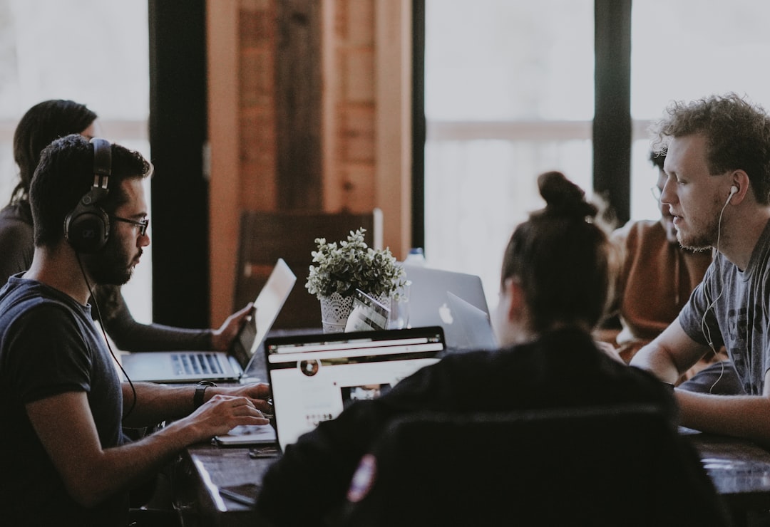 selective focus photography of people sits in front of table inside room software team ecommerce planning office