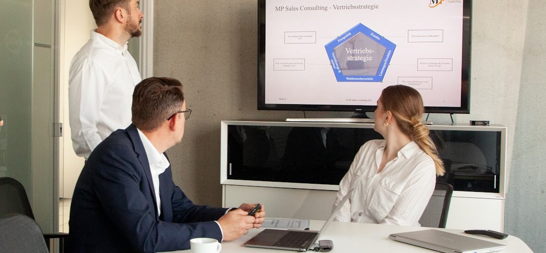 three people in a meeting room looking at a presentation logistics team crm dashboard freight sales 2