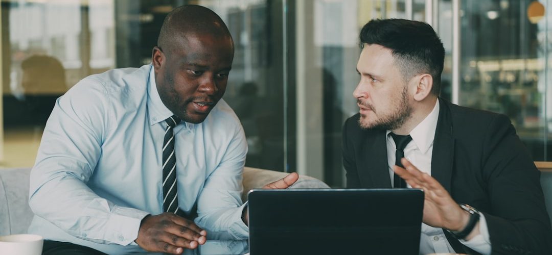 two businessmen collaborating over a tablet and laptop sales team customer discussion business value