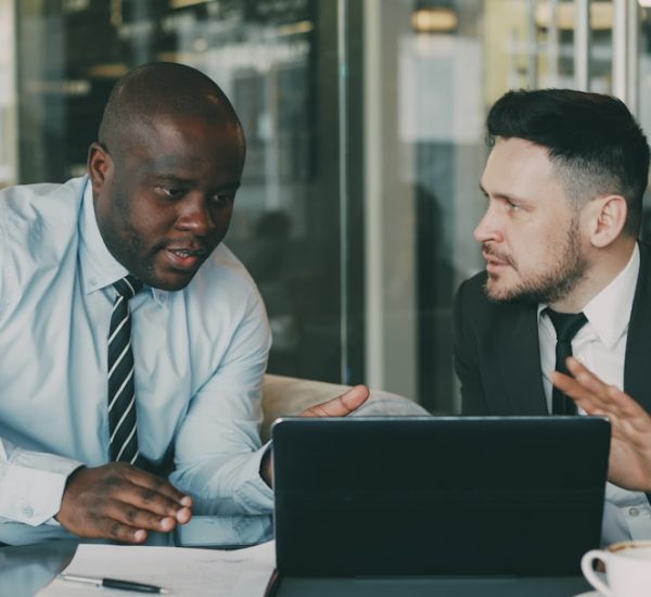 two businessmen collaborating over a tablet and laptop sales team customer discussion business value
