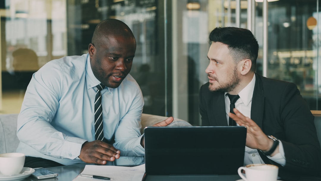 two businessmen collaborating over a tablet and laptop sales team customer discussion business value