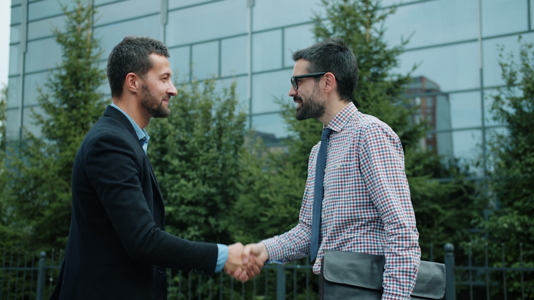 two businessmen shaking hands outside an office building outside sales client meeting business travel handshake