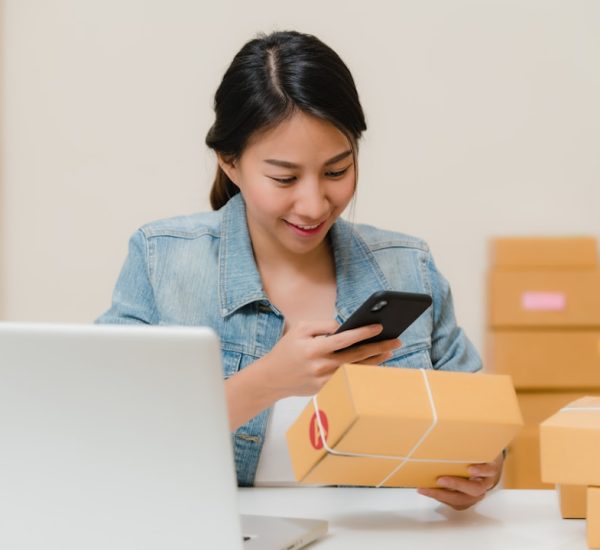 Amazon Search Engine Marketing: How to Increase Product Visibility 8 woman checking package with phone near laptop and boxes online store analytics mobile commerce