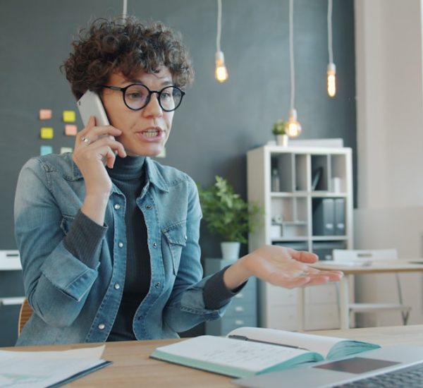 Service Management: Definition, Processes, Frameworks, and Best Service Management Tools 10 woman talking on phone at desk with laptop support agent headset customer conversation service desk