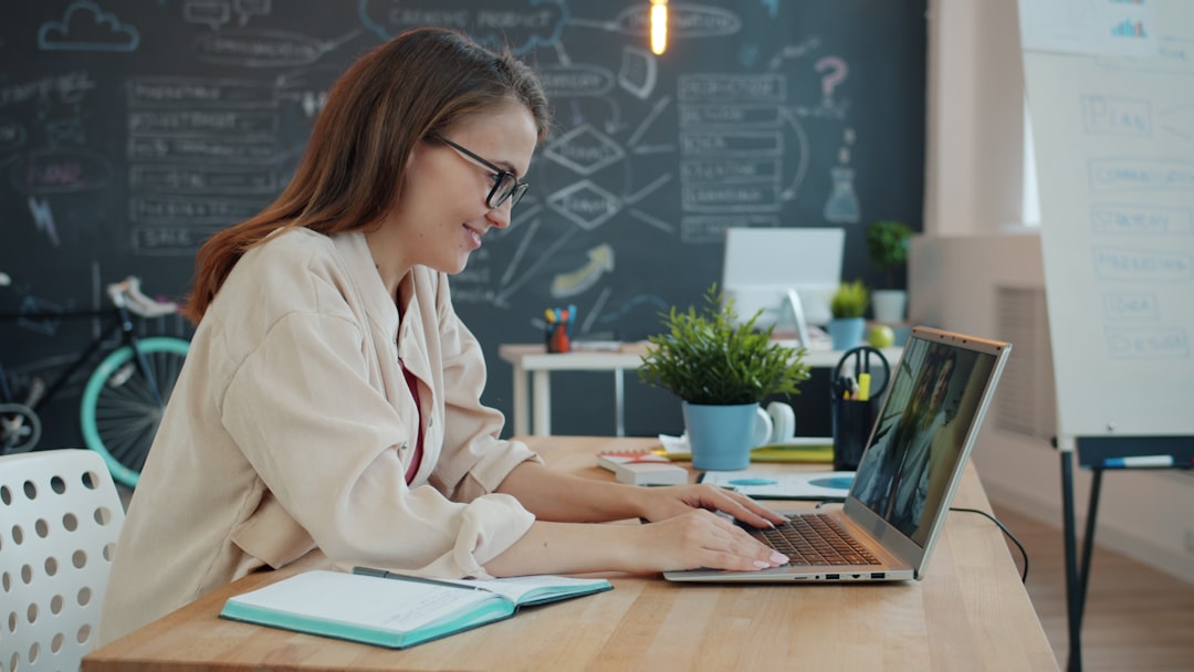 young woman working on laptop in modern office remote team video call virtual workspace