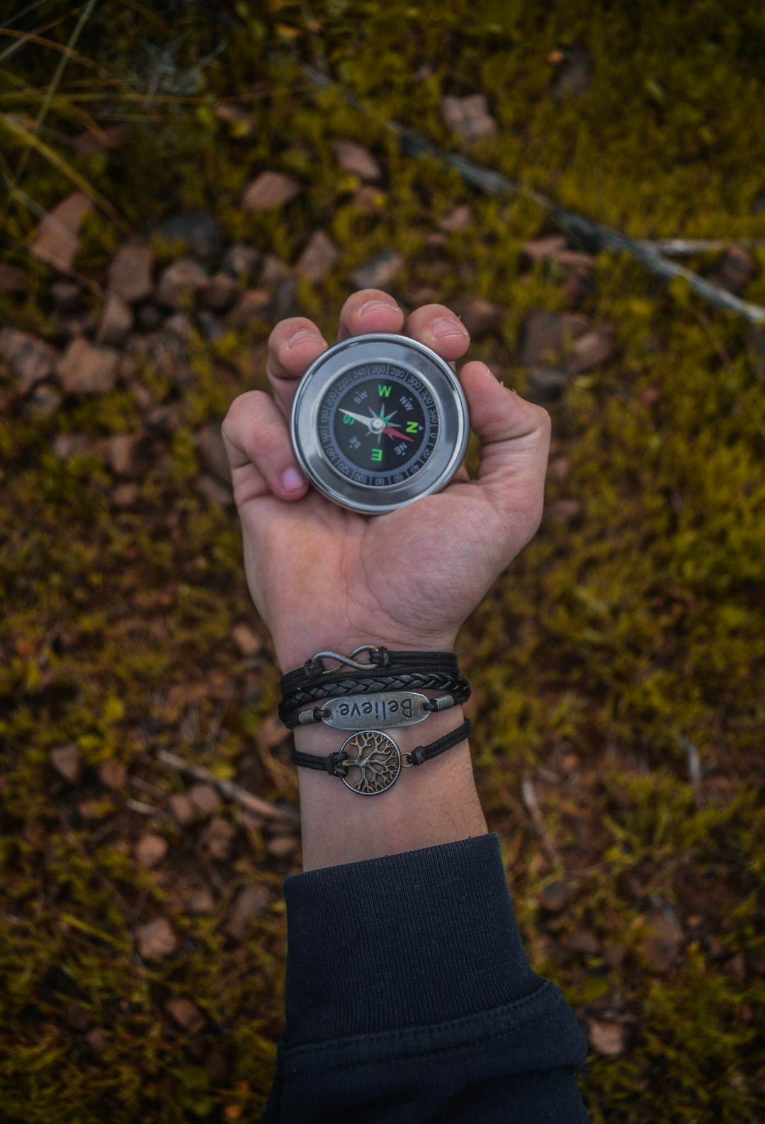 a person holding a compass in their hand topographic map compass hiking gear forest
