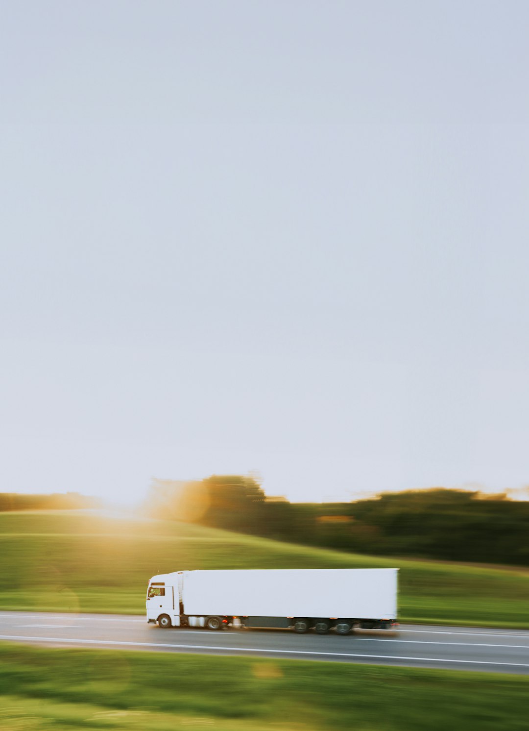 a white truck driving down a road next to a lush green field logistics team route planning freight software