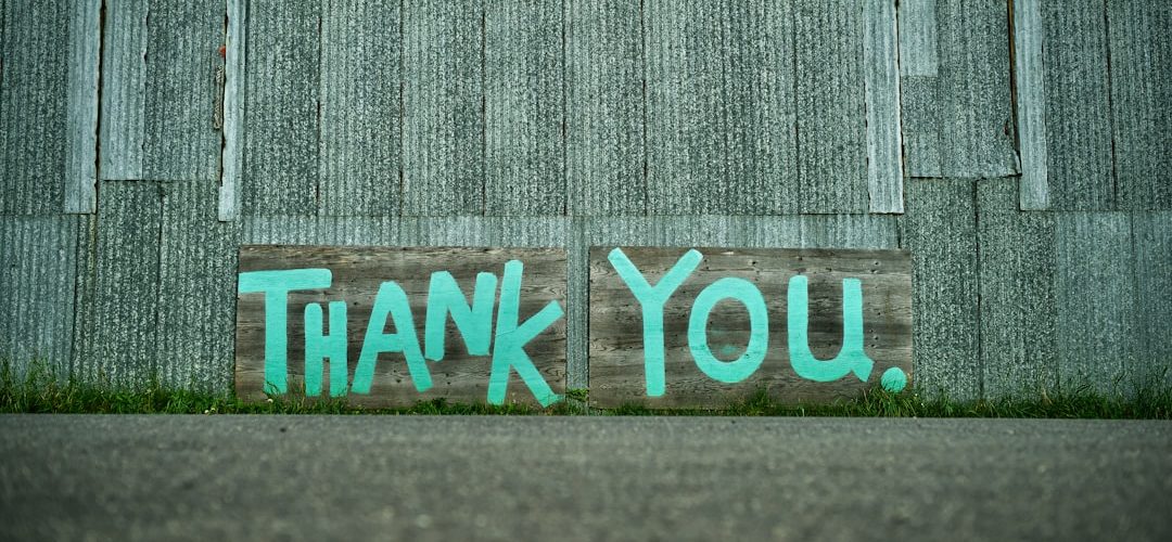a wooden sign painted with the words thank you against a corrugated metal wall fundraising team donor thank you nonprofit office