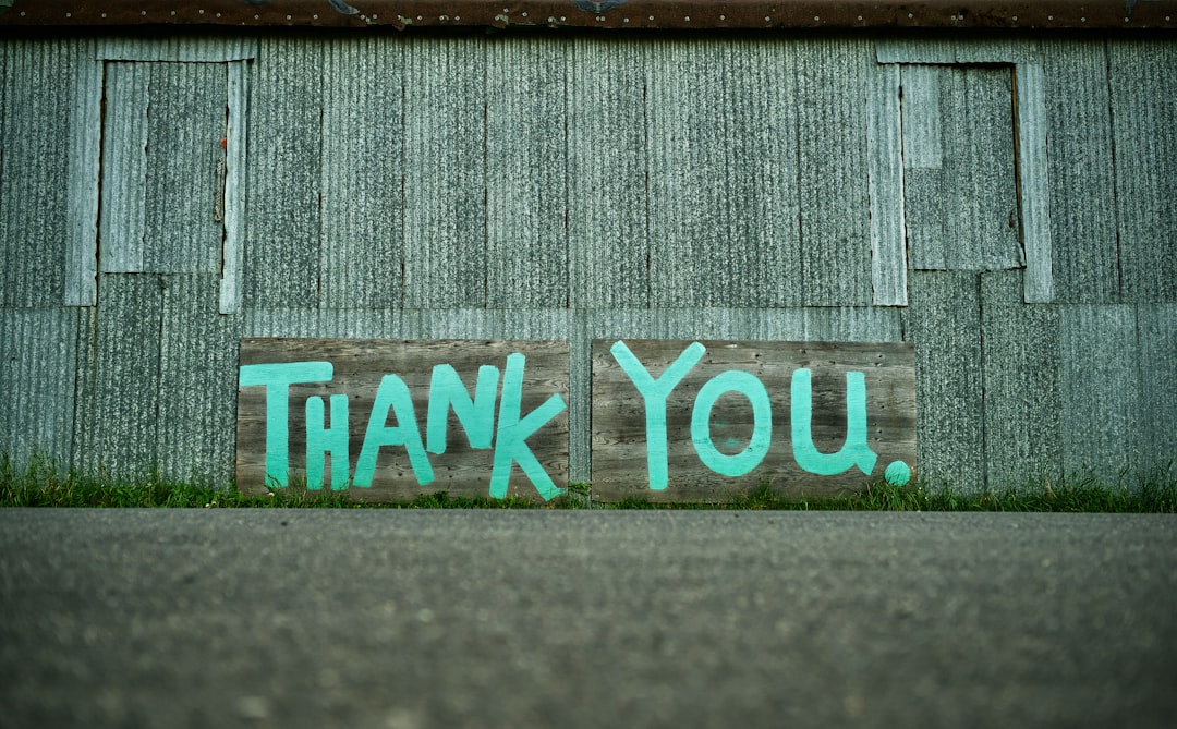 a wooden sign painted with the words thank you against a corrugated metal wall fundraising team donor thank you nonprofit office