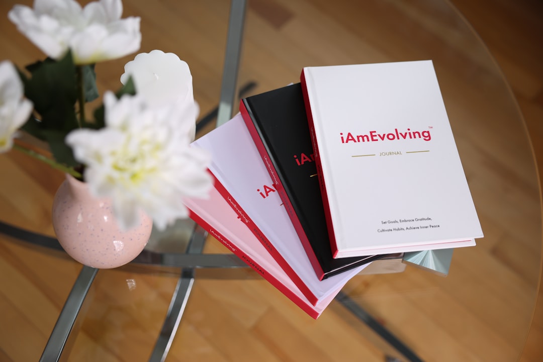 books stacked on a glass table with flowers personal development habits journal wellness