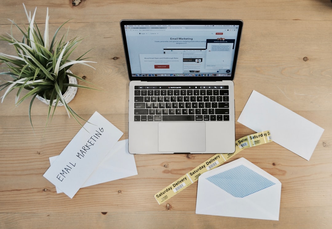 macbook pro beside white papers and plant small business owner email marketing ecommerce analytics