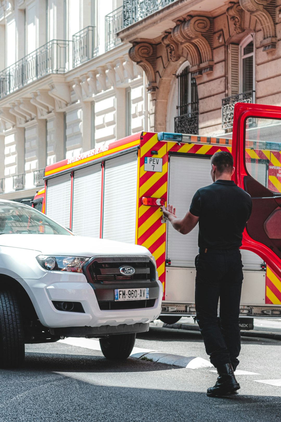 man in black t shirt and black pants standing beside white ford suv during daytime staff scheduling compliance records emergency vehicles