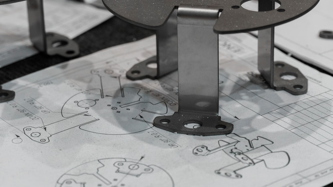 metal components resting on engineering blueprints cad software comparison laptop design engineering tools 3d models