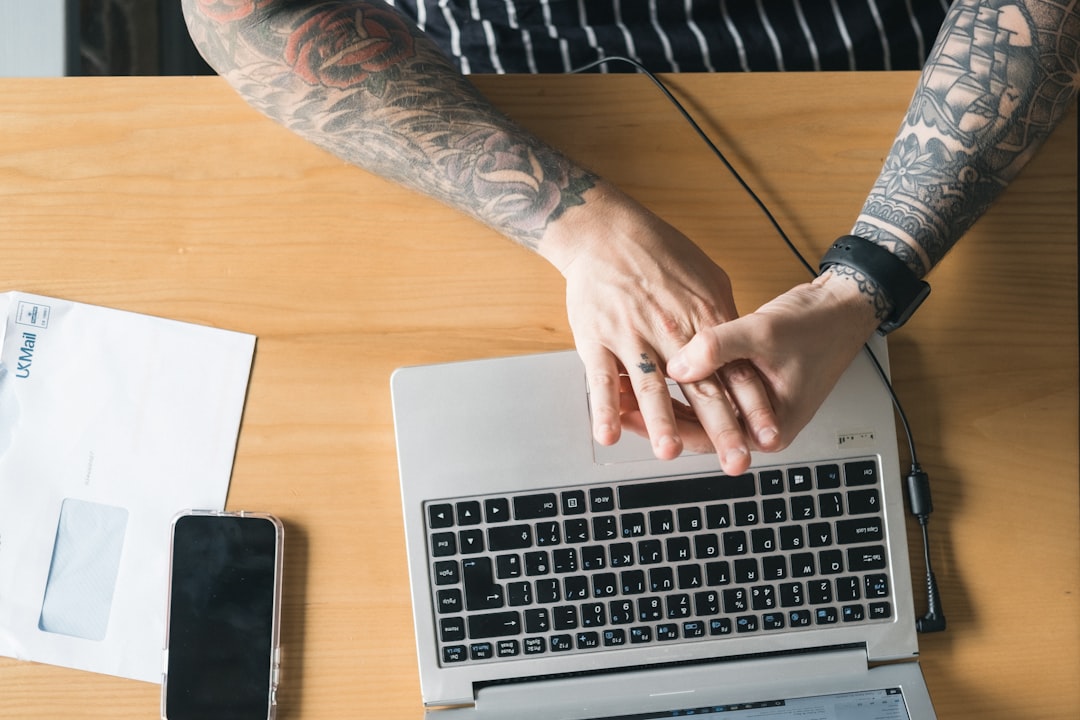 person using macbook pro on brown wooden table small business owner email marketing ecommerce analytics