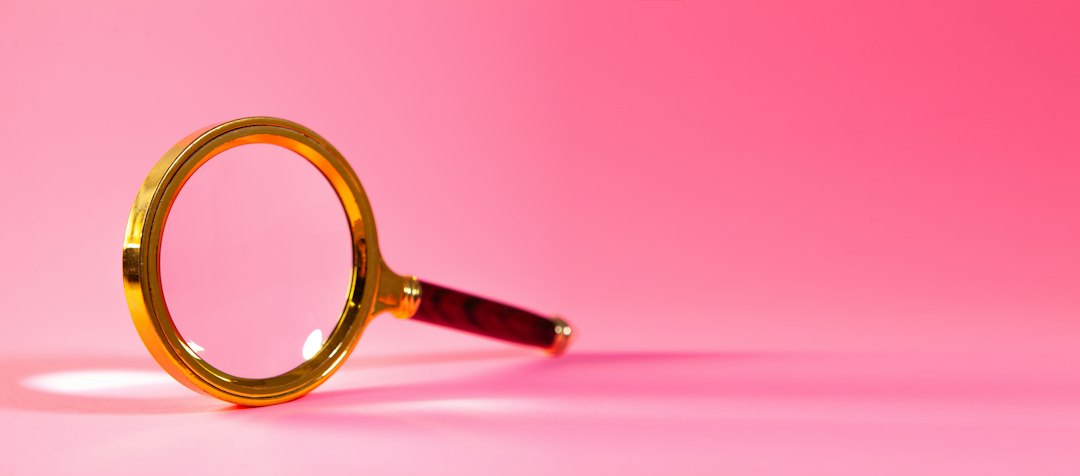 a magnifying glass on a pink background identity check profile cards magnifying glass