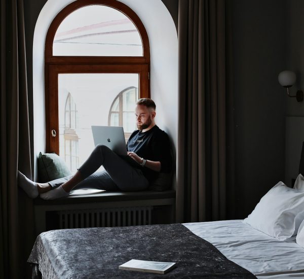 Hospitality Industry Mailing List: Mailchimp vs HubSpot for Hospitality Email Marketing 8 a man sitting on a bed using a laptop computer hotel email dashboard guest segments booking campaign
