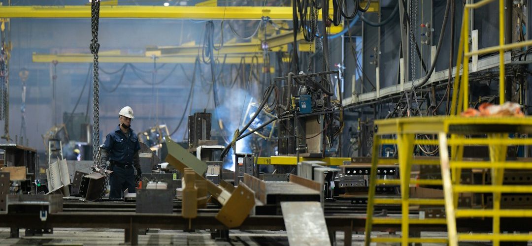 a man standing in front of a machine in a factory cnc machine operator control panel metal shop