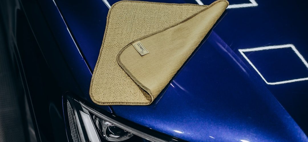 a microfiber cloth rests on a shiny blue car scratched cd microfiber cloth bright light