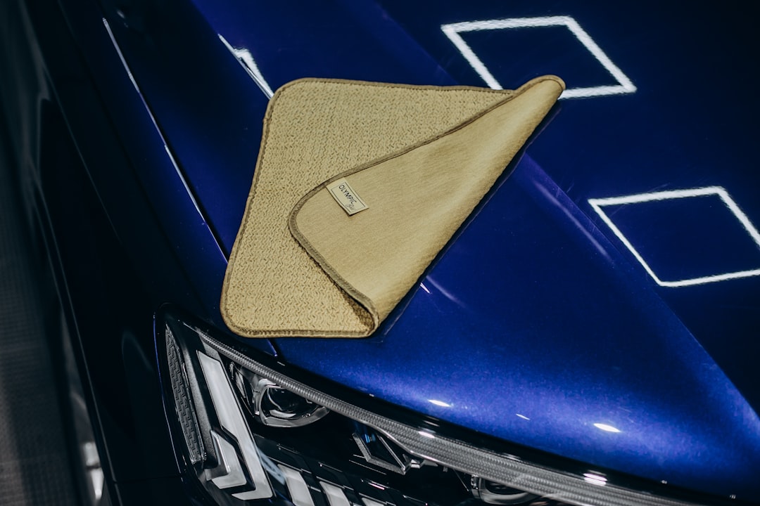 a microfiber cloth rests on a shiny blue car scratched cd microfiber cloth bright light