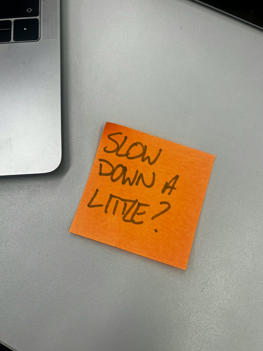 a piece of orange paper with the words slow down 4 little written on it product team design review sticky notes laptop screens
