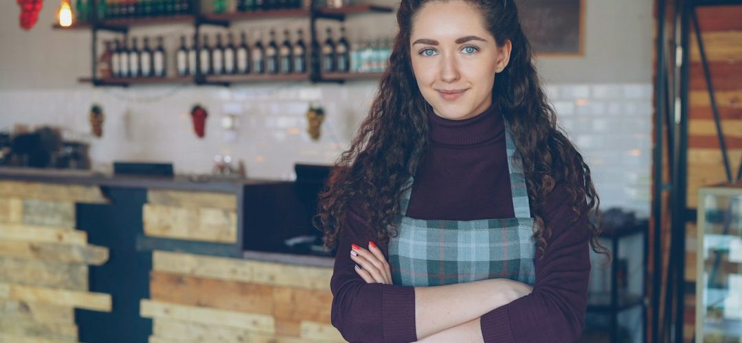 a smiling woman stands in her coffee shop small business owner email template online store