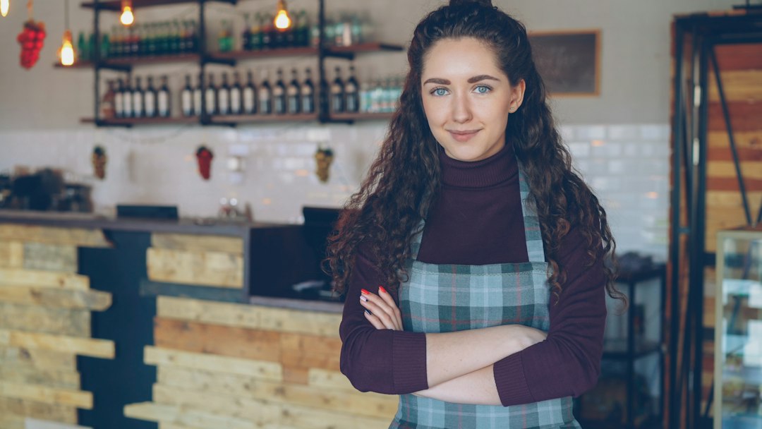 a smiling woman stands in her coffee shop small business owner email template online store