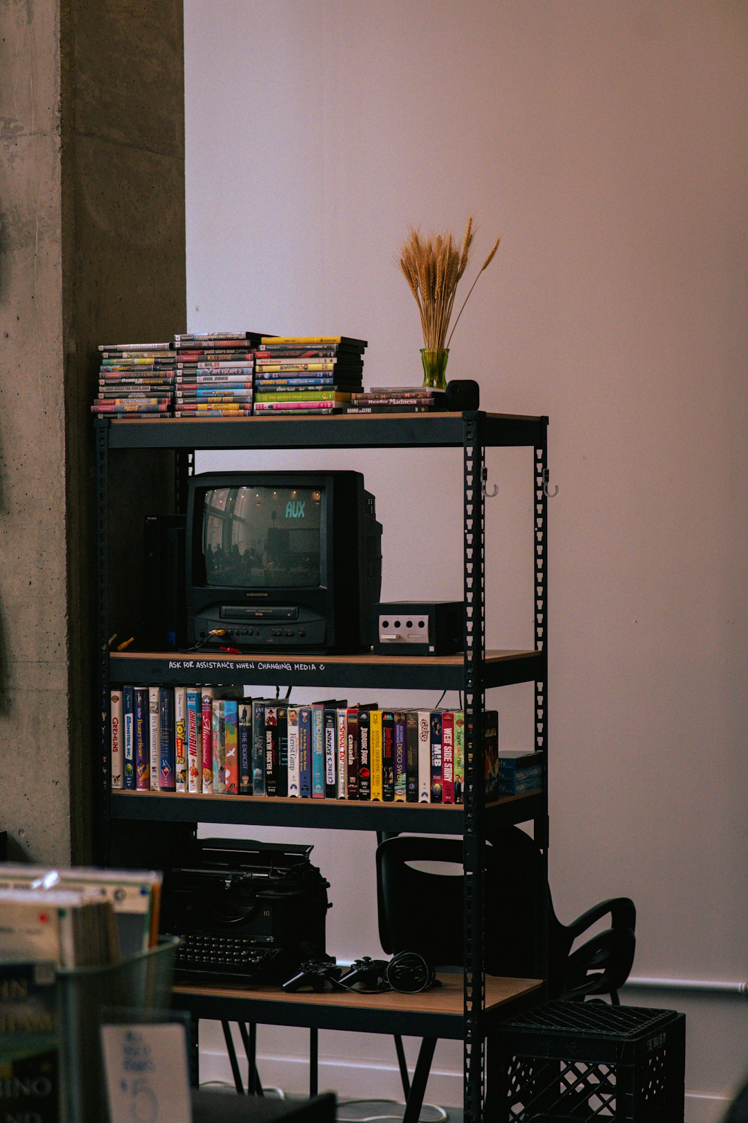 shelf with old television vhs tapes and typewriter cd storage jewel cases organized shelf