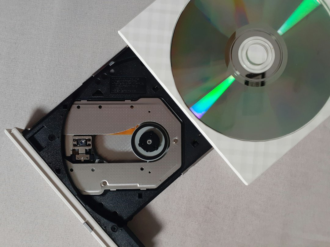 silver compact disc on black cd rack dvd player movie night clean disc
