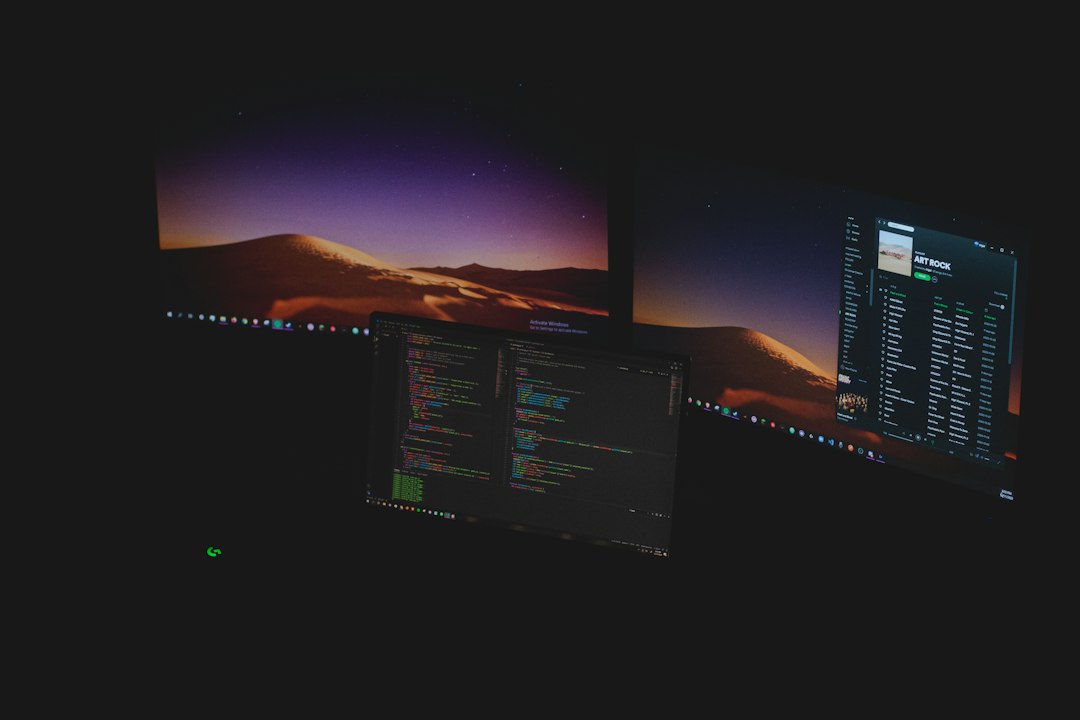 three computer monitors displaying code and music software in a dark room no code app builder startup dashboard product prototype