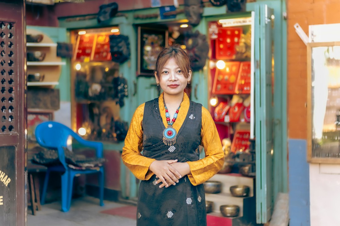 woman in traditional clothing stands in shop host greeting guests travel welcome front door warm smile