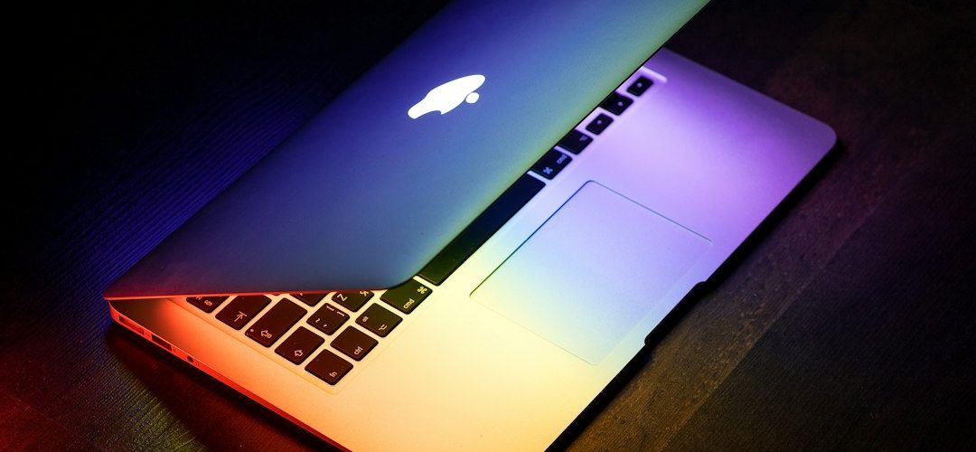 a macbook lit up in rainbow colors on a wooden surface laptop screen patches colored blocks display defect