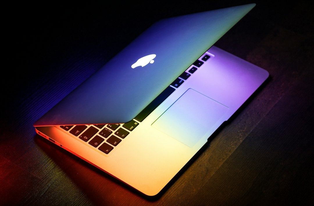 a macbook lit up in rainbow colors on a wooden surface laptop screen patches colored blocks display defect
