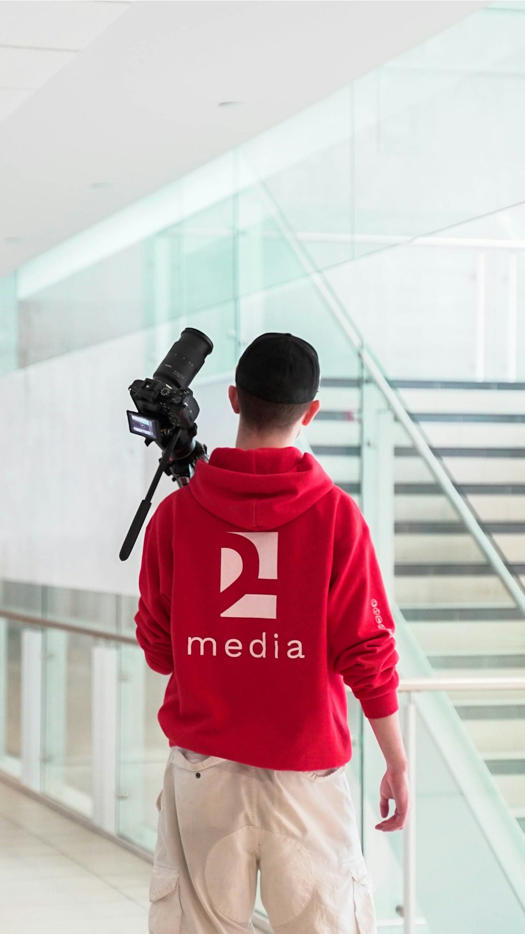 a man in a red hoodie is holding a camera journalist research media outreach targeted pitching