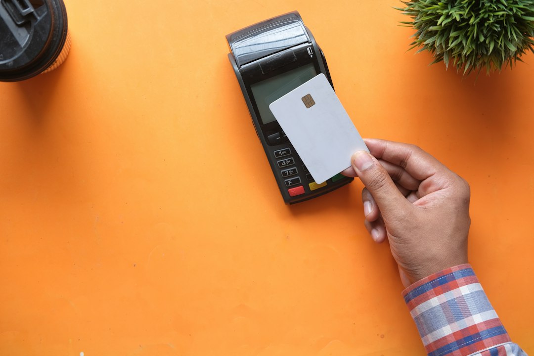 a person holding a blank credit card near a payment terminal on orange instant payments bank transfer small business finance