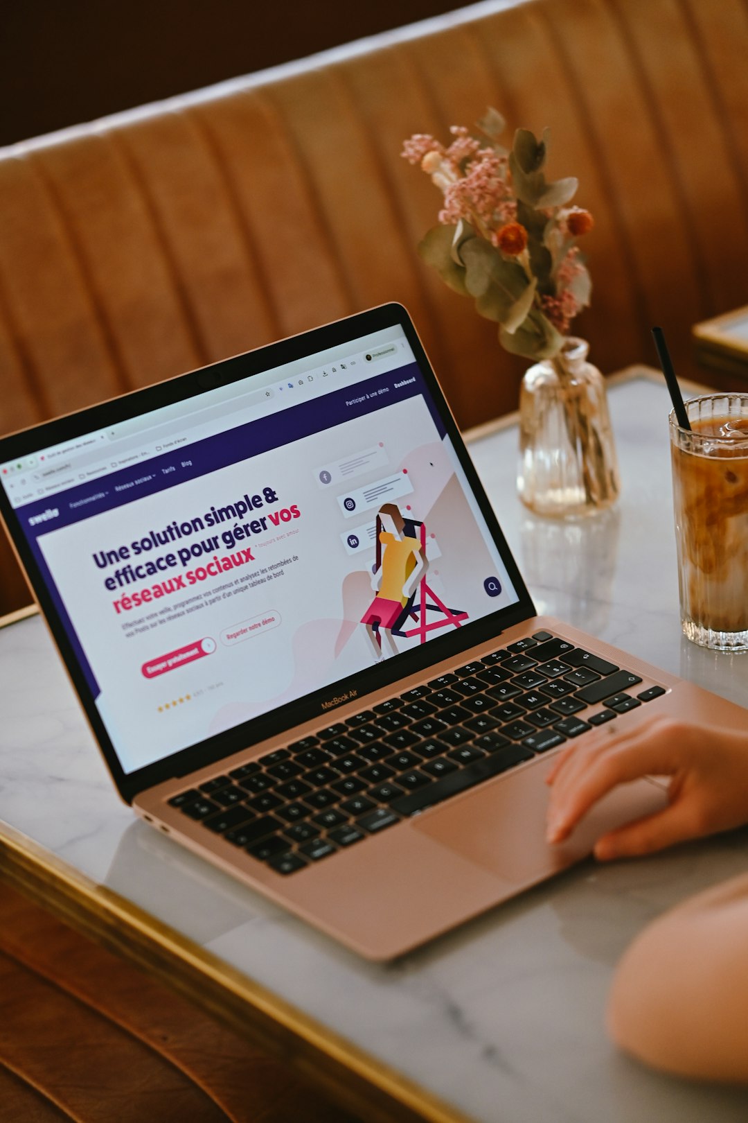 a person using a laptop on a marble table with iced coffee and flowers brand dashboard visibility chart competitor tracking