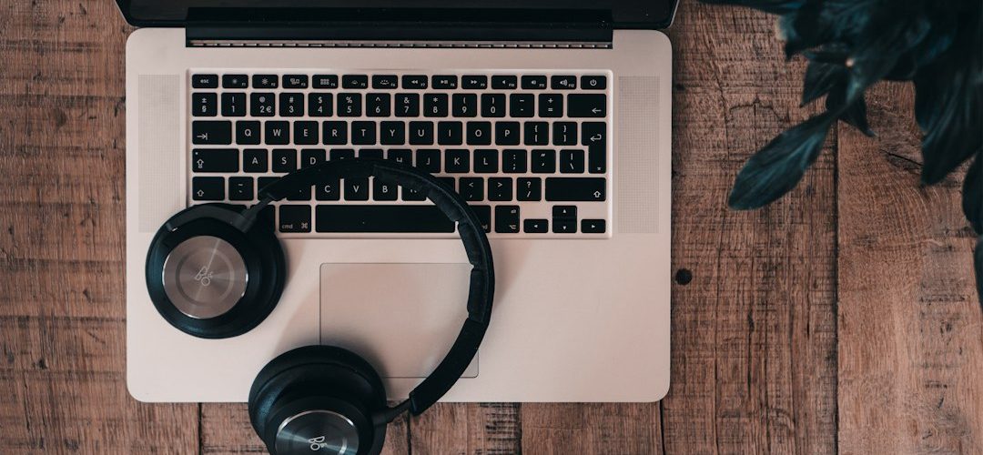black cordless bluetooth headphones on top of macbook pro headphones laptop warning icons