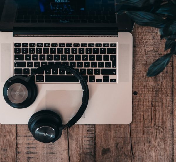 black cordless bluetooth headphones on top of macbook pro headphones laptop warning icons